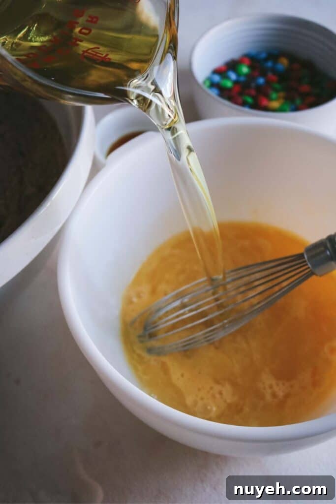 adding vegetable oil to whisked eggs.