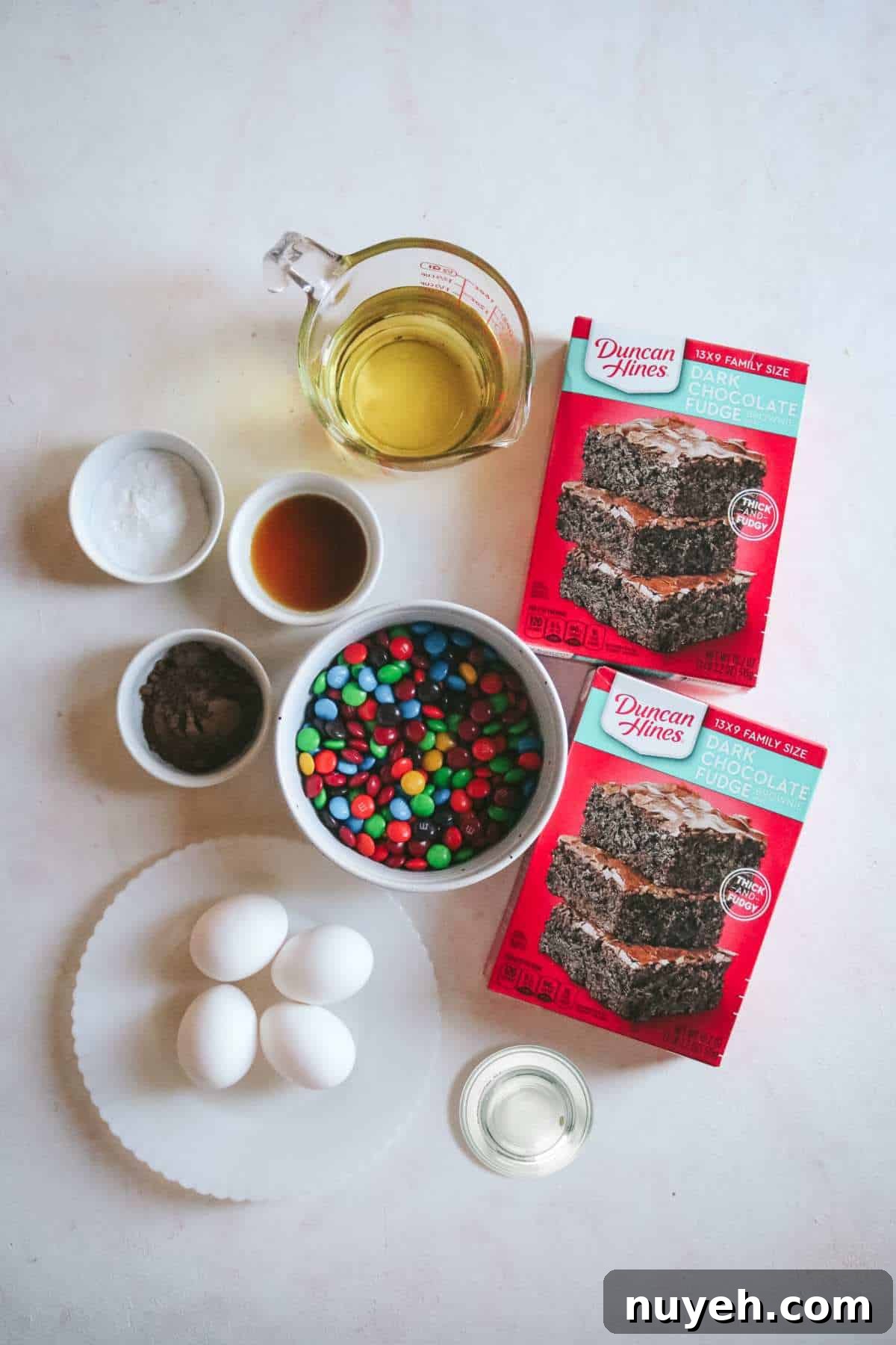 overhead view of all the ingredients to make fudgy m&m brownies including water, oil, brownie mix, eggs, and more.
