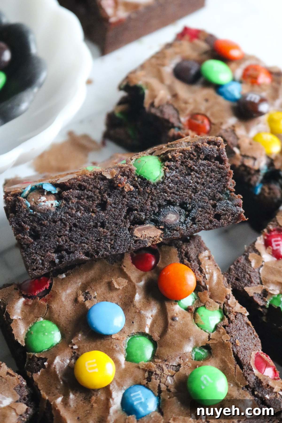 side view of a sliced m&m brownie with lots candies inside and sprinkled over top.