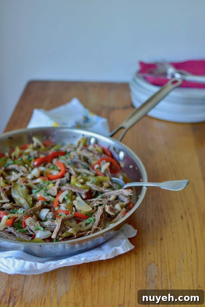 A stainless steel pan with Cuban Ropa Vieja on a wooden table.