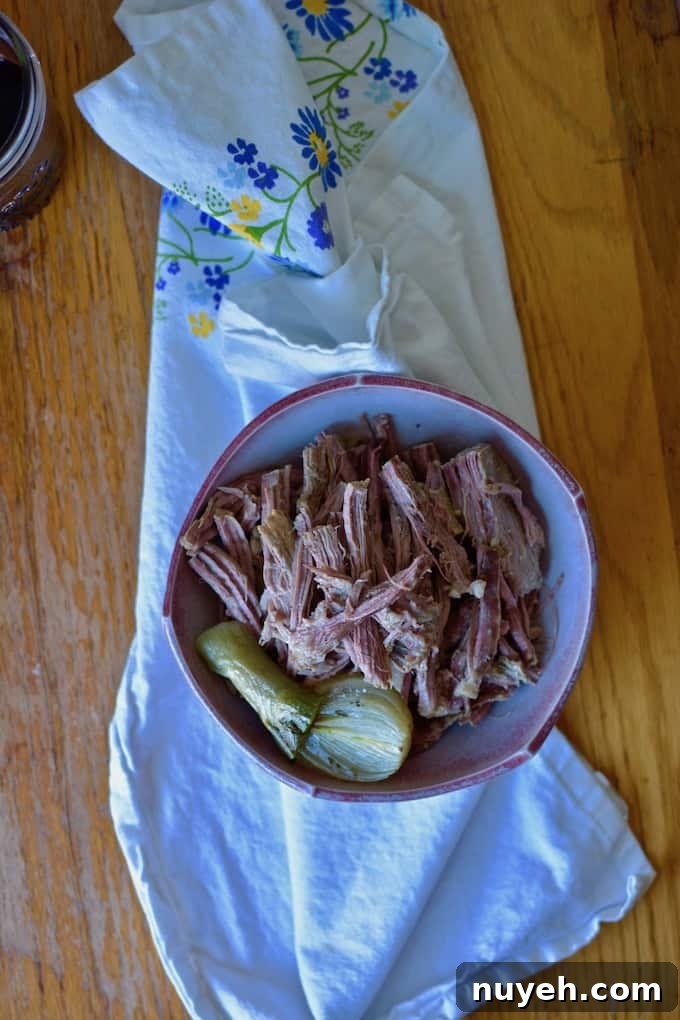 A bowl of shredded beef and cooked onions on a cloth.