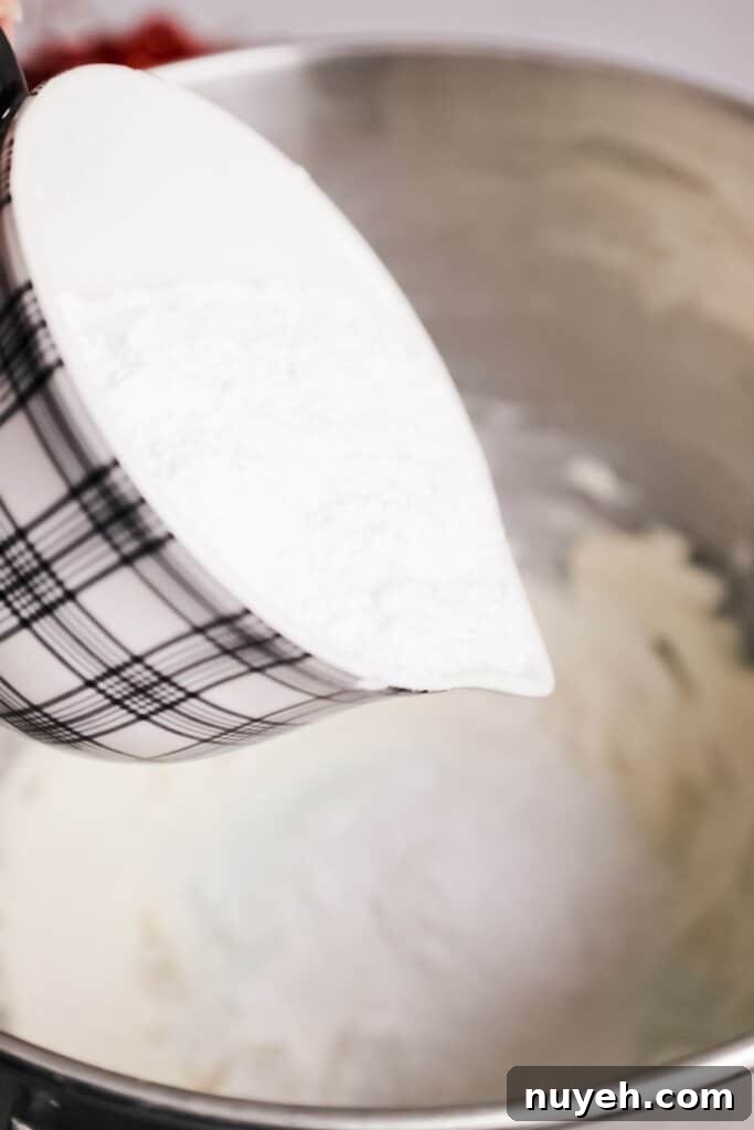 Powdered sugar being added to butter in a bowl.