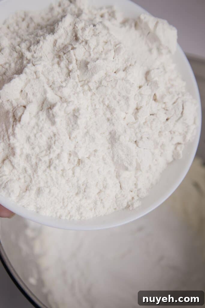 Flour being added to dough in a mixing bowl.
