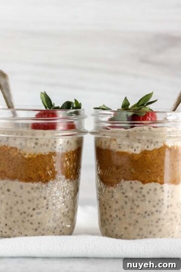 Two mason jars filled with overnight oats and almond butter topped with a strawberry.