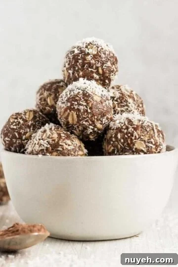 Chocolate peanut butter balls sprinkled with coconut flakes stacked in a small white bowl.