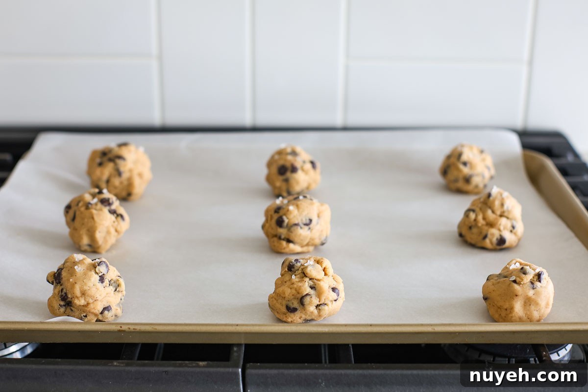 Dough balls placed in a lined baking sheet.