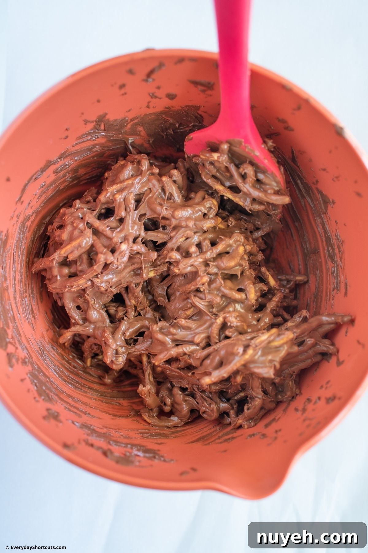 Homemade Birds Nest Cookies with Chocolate Eggs 5 combining chow mein noodles and melted chocolate in a bowl