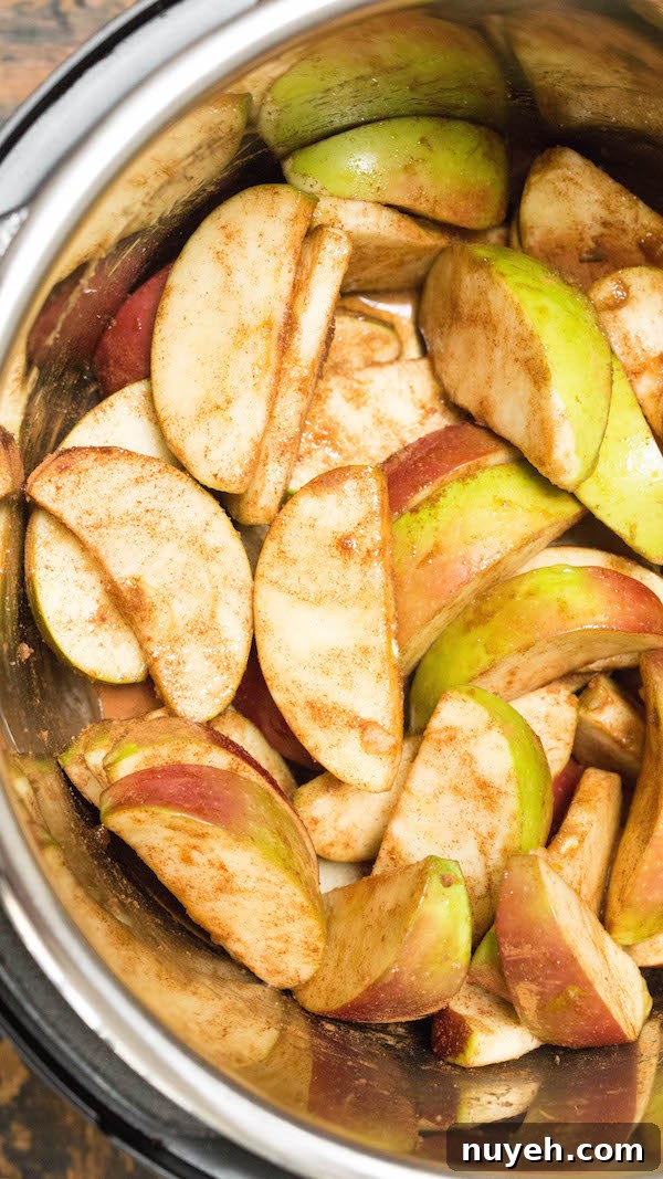 Apple cider being poured over sliced apples and brown sugar in the Instant Pot to make apple butter.
