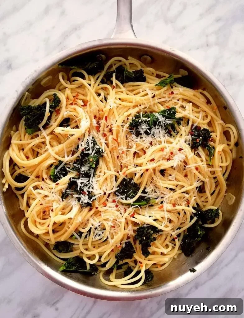 spicy kale pasta in skillet topped with parmesan and red pepper flakes