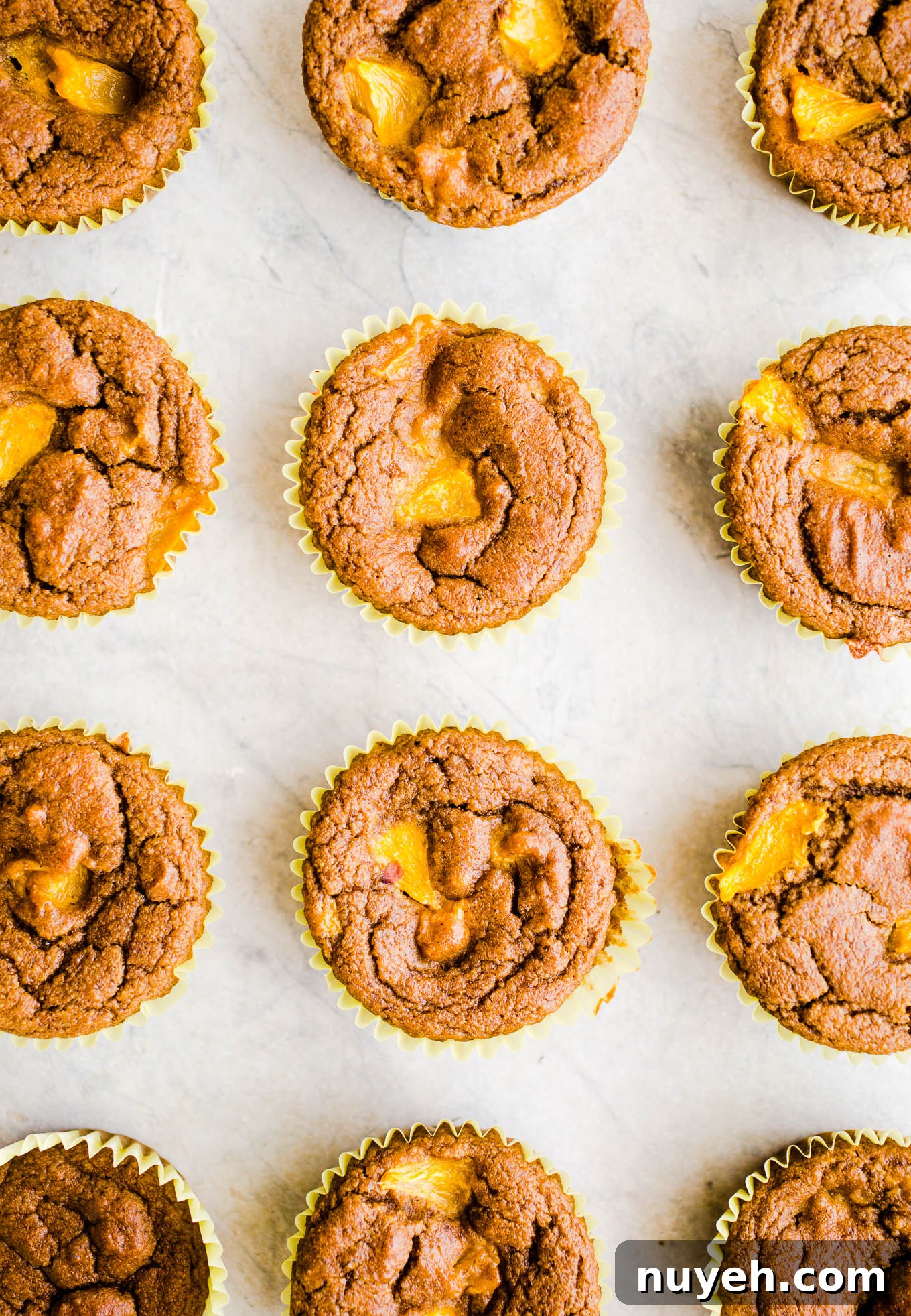 Fresh peach muffins on a marble surface.