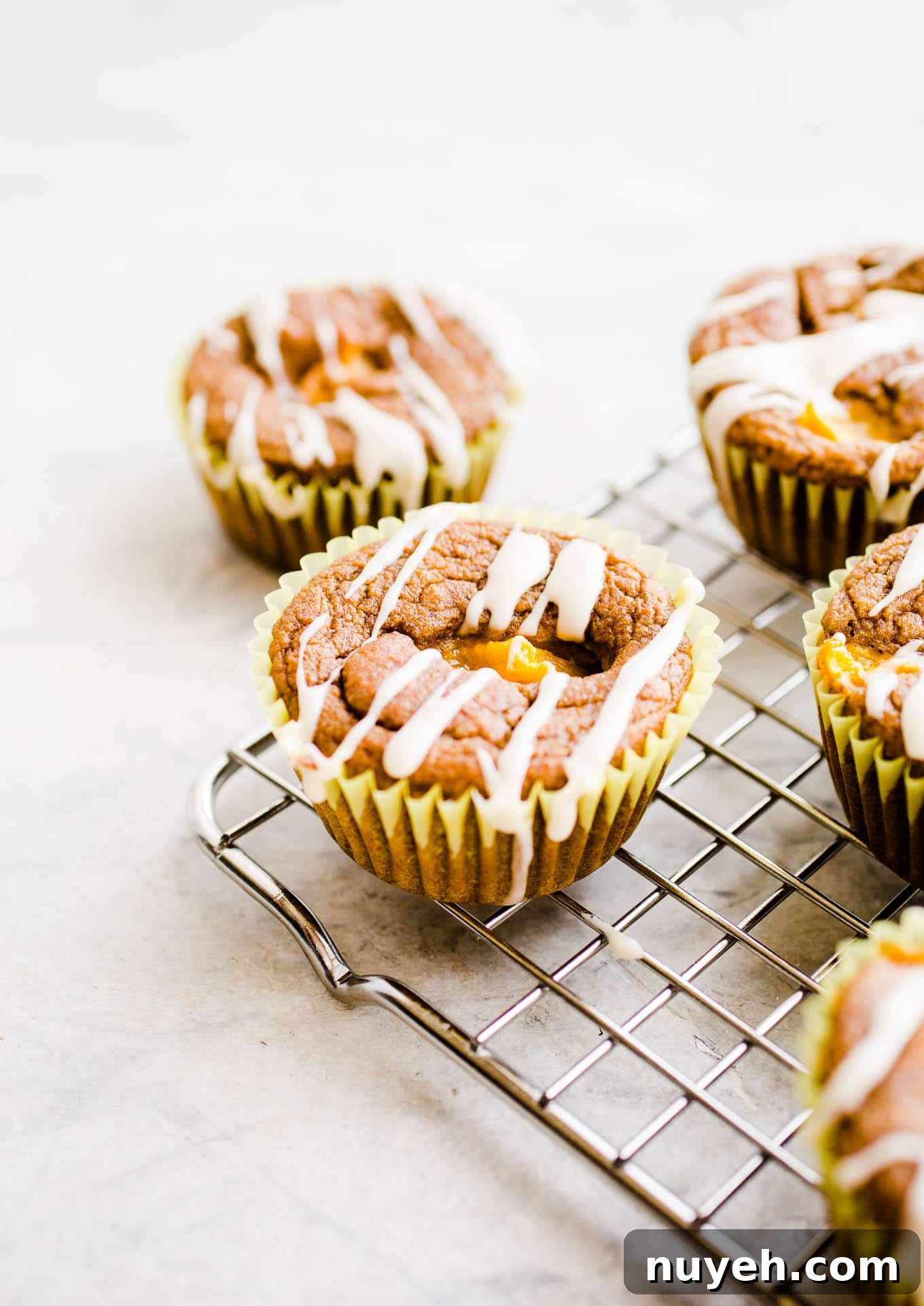 Iced peach muffins on a wire cooling rack.