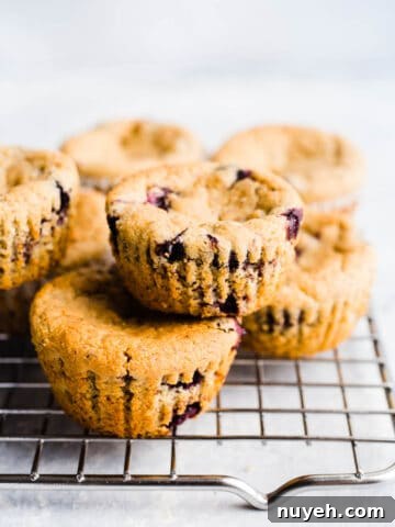 Blueberry muffins stacked two by two on a wire rack.