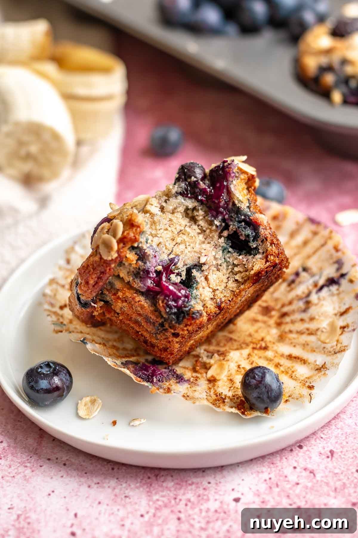 Blueberry muffin on a plate with a bite removed.