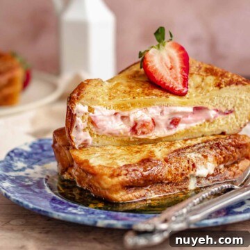 Two stacks of strawberry stuffed French toast on a plate.