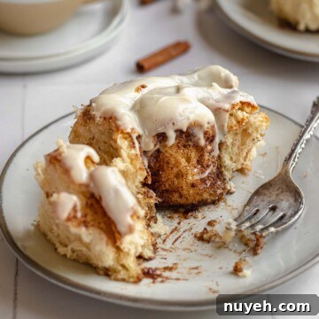 Brioche cinnamon roll on a plate with bites removed from a fork.