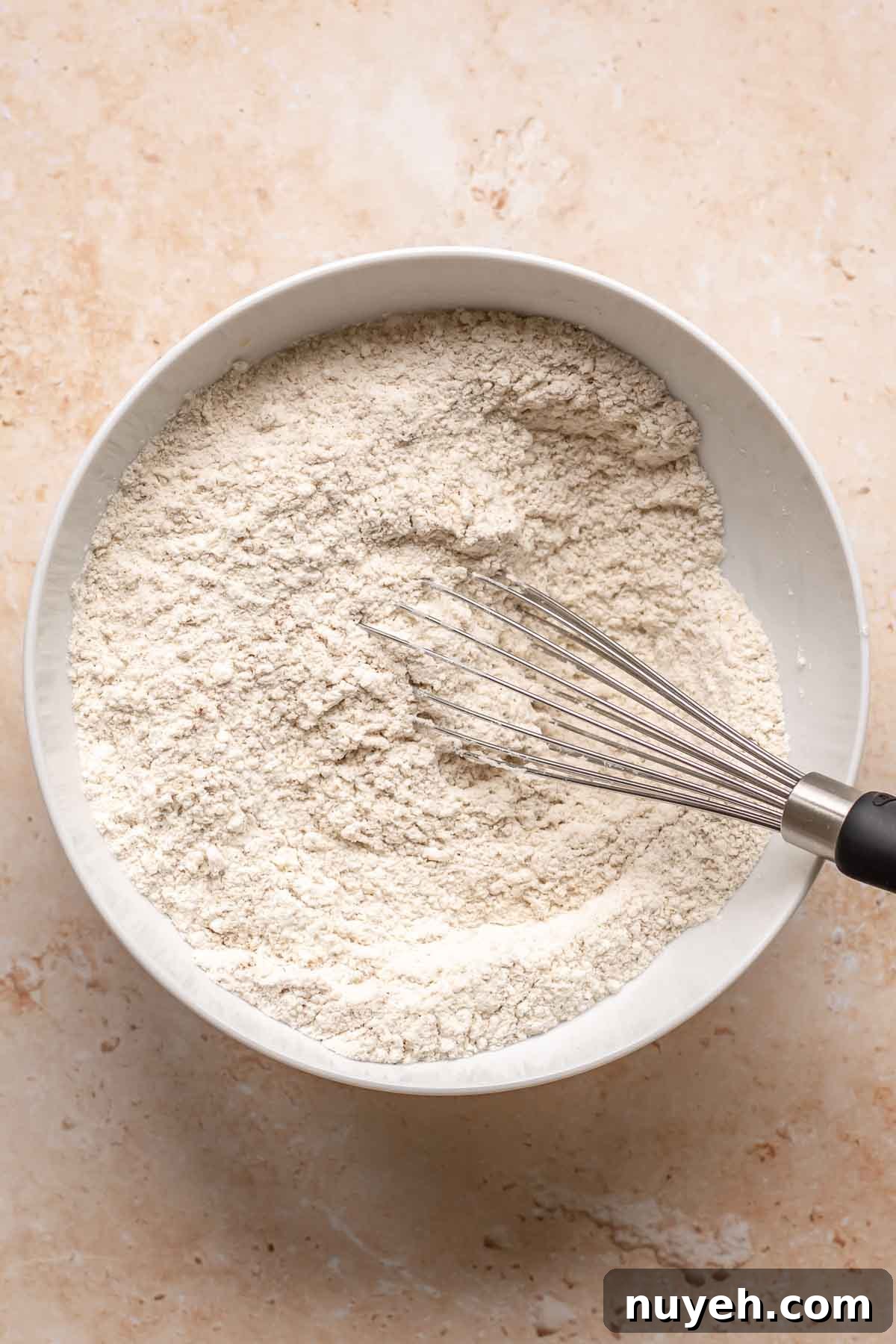 Dry ingredients in a bowl with a whisk.