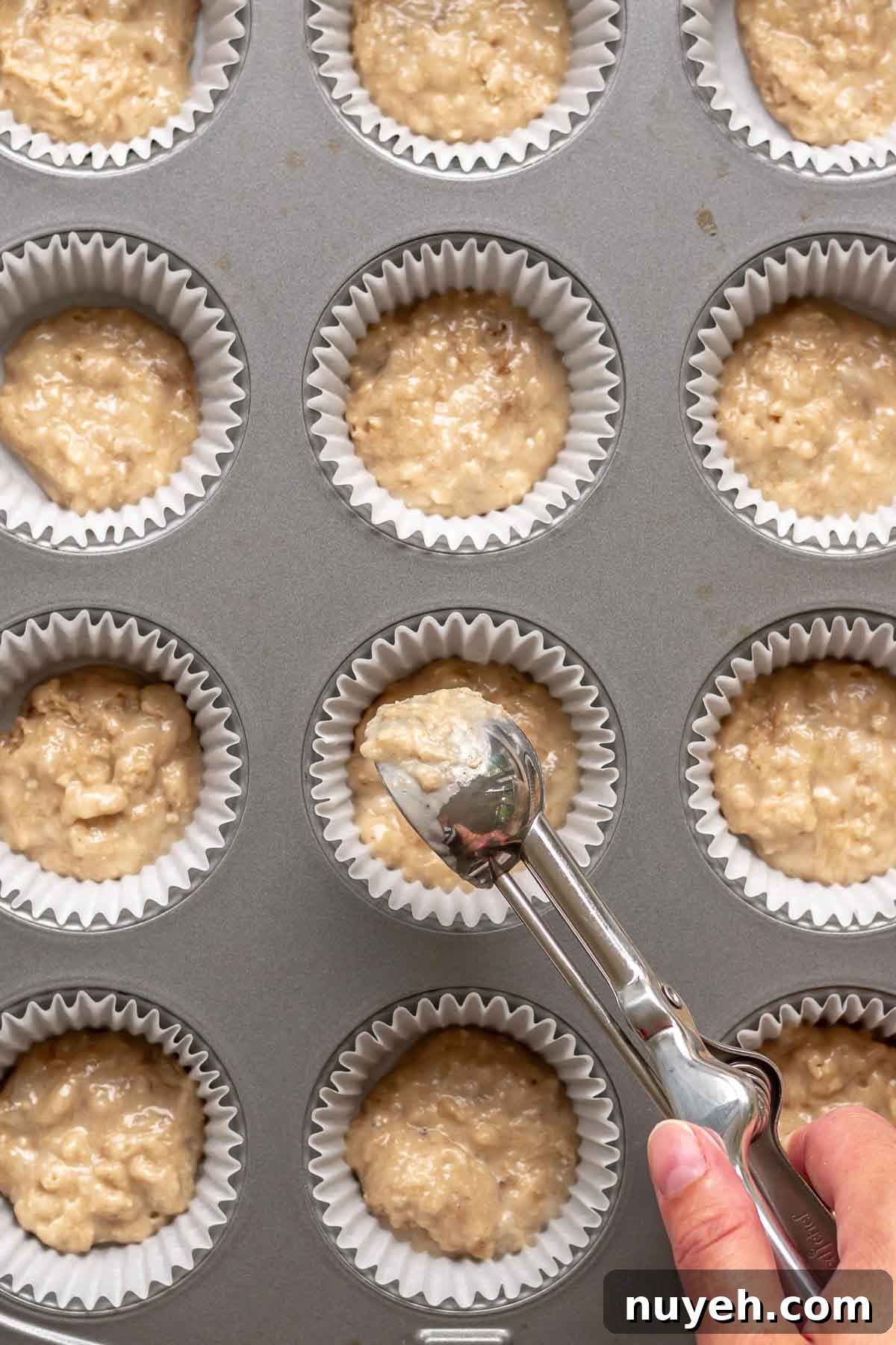 A cookie scoop adds a small amount of muffin batter to cupcake liners.