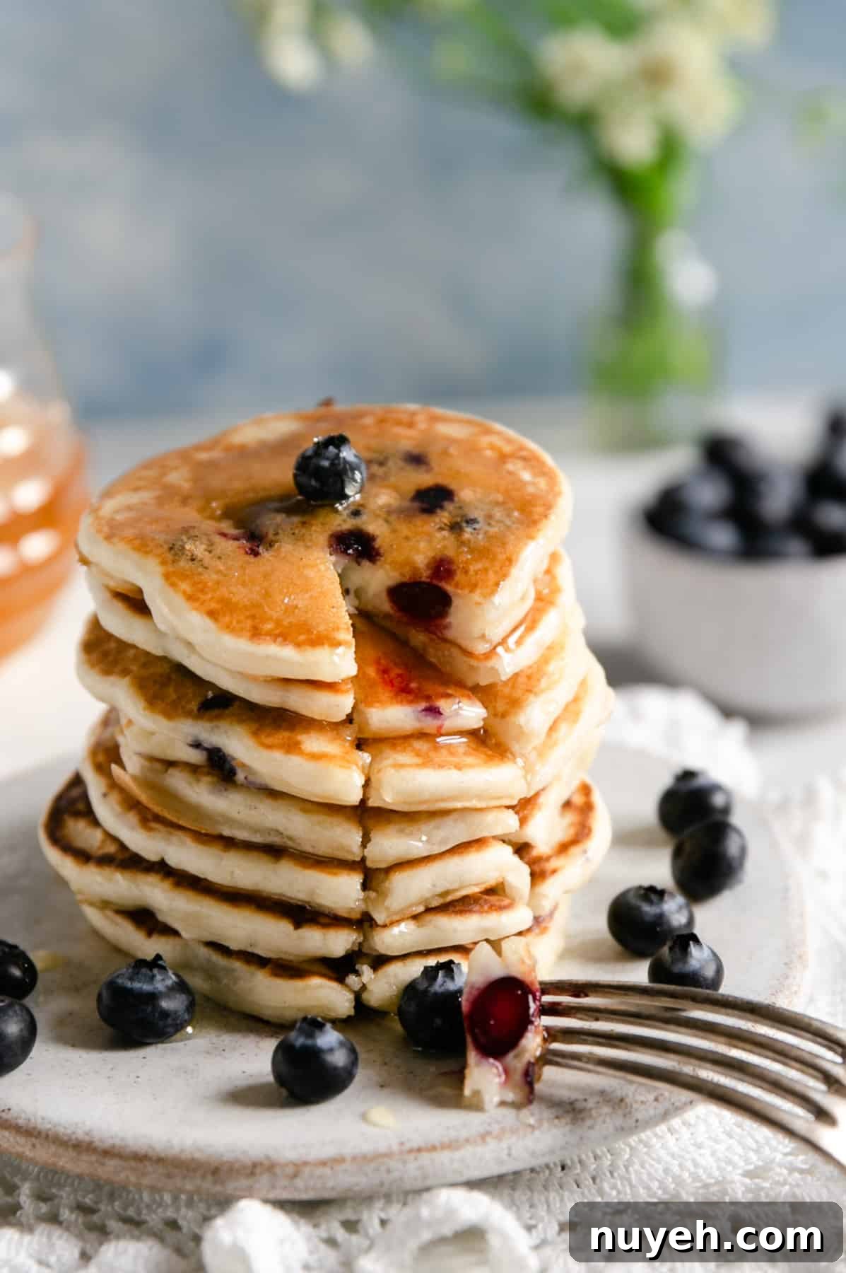 Straight ahead shot of stack of golden blueberry pancakes with a segment cut out