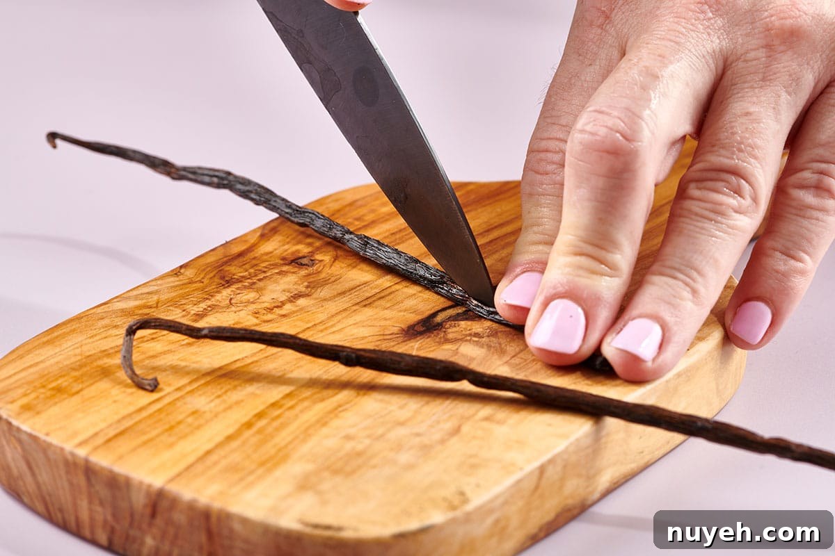 Katie Workman slicing vanilla bean with knife on cutting board.