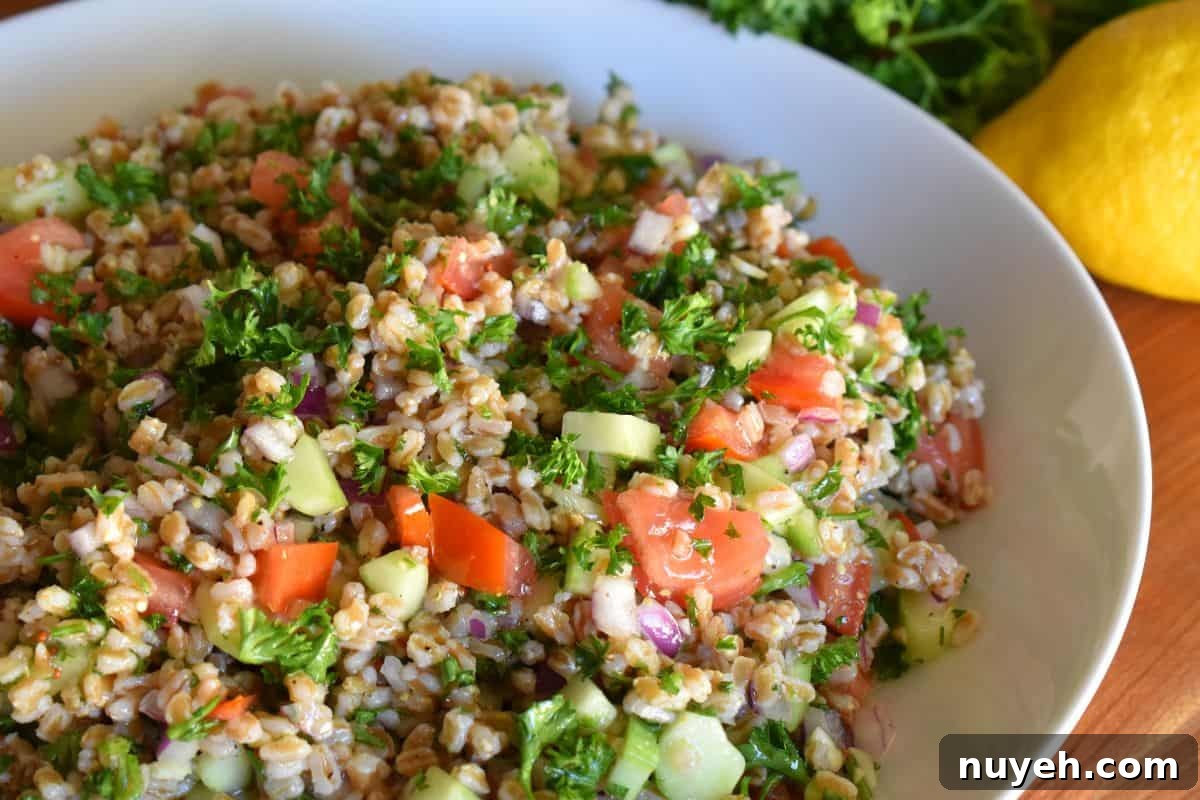 Farro Tabbouleh salad in a white bowl with lemon next to it. 