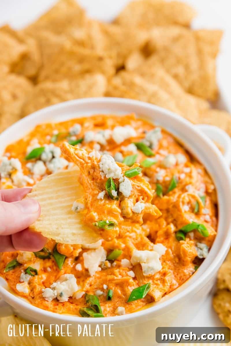 a hand dipping a chip into buffalo chicken dip