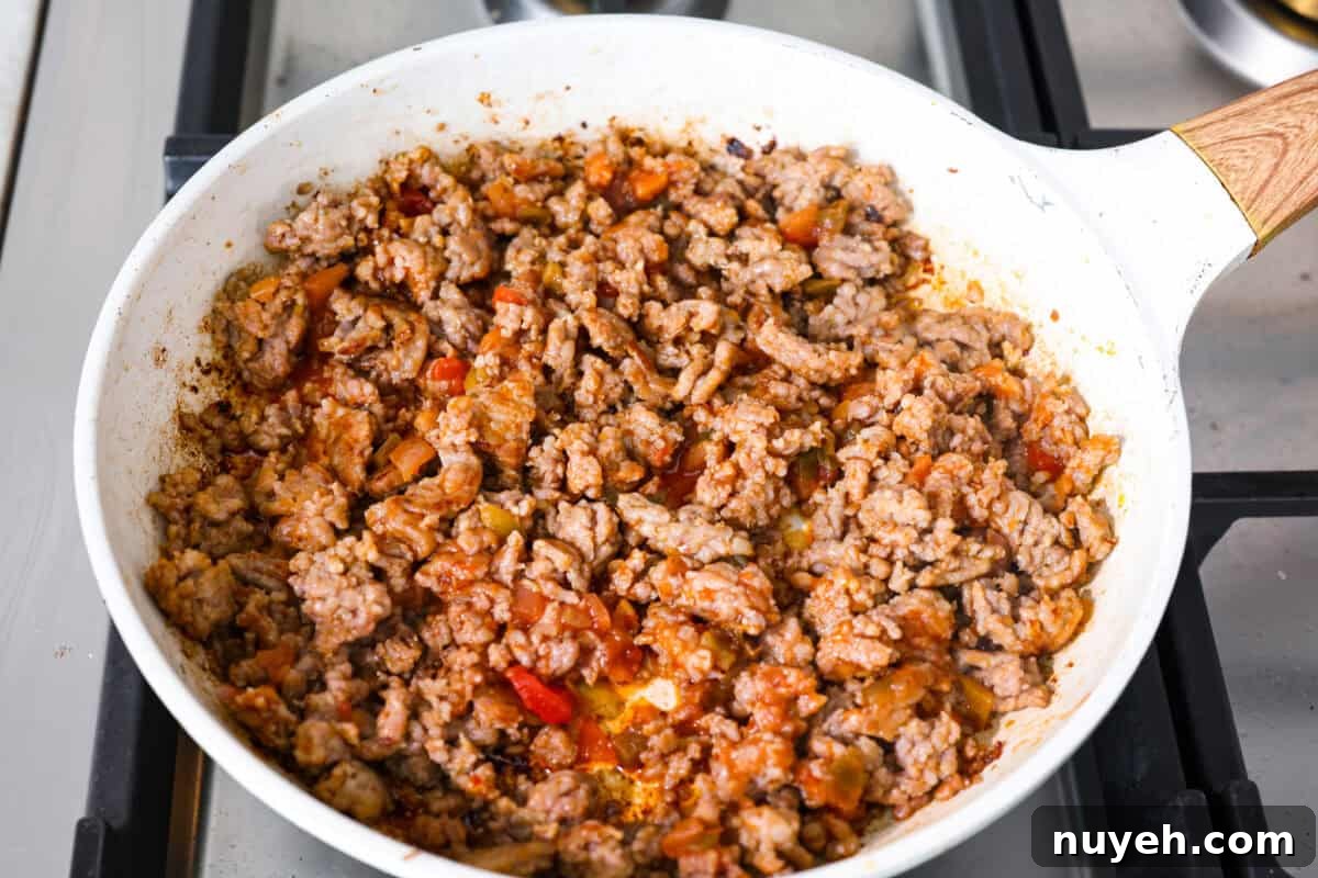 Sausage cooking in a skillet with salsa added