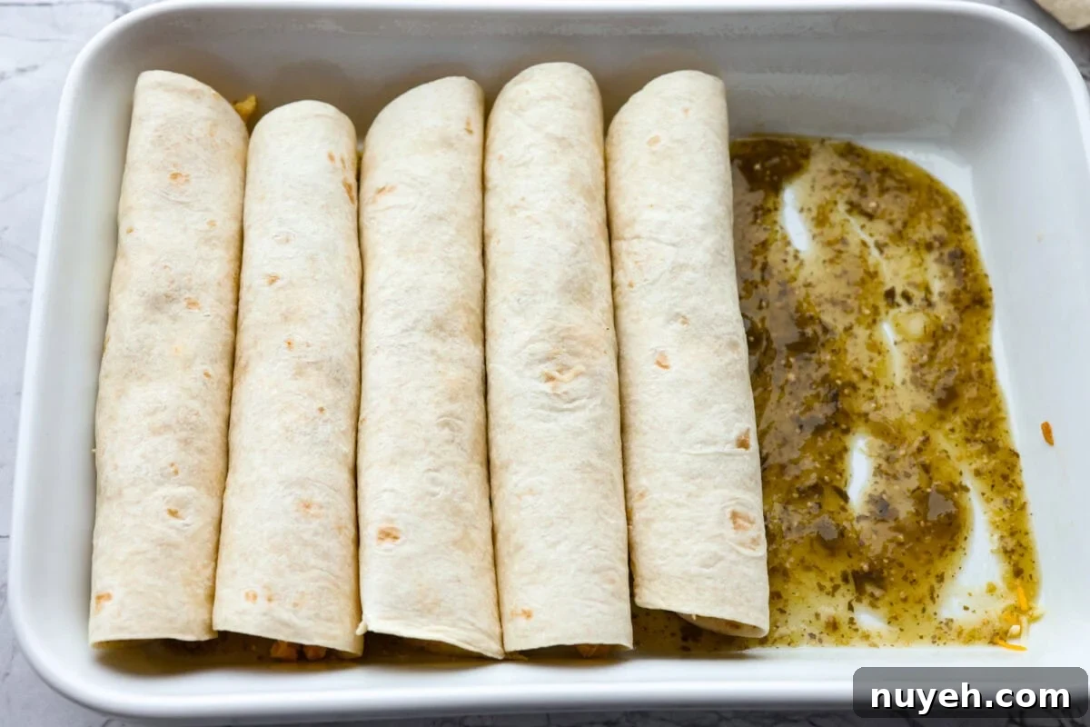 Rolled enchiladas in a pan with salsa verde on the bottom