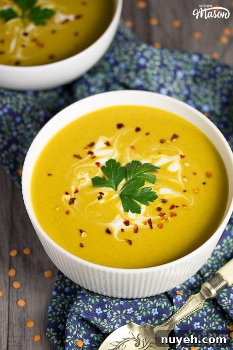 curried coconut lentil soup in a bowl with parsley and chilli flakes on top