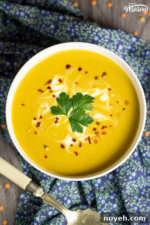 curried coconut lentil soup in a bowl with parsley and chilli flakes on top