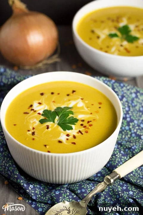 curried coconut lentil soup in a bowl with parsley and chilli flakes on top