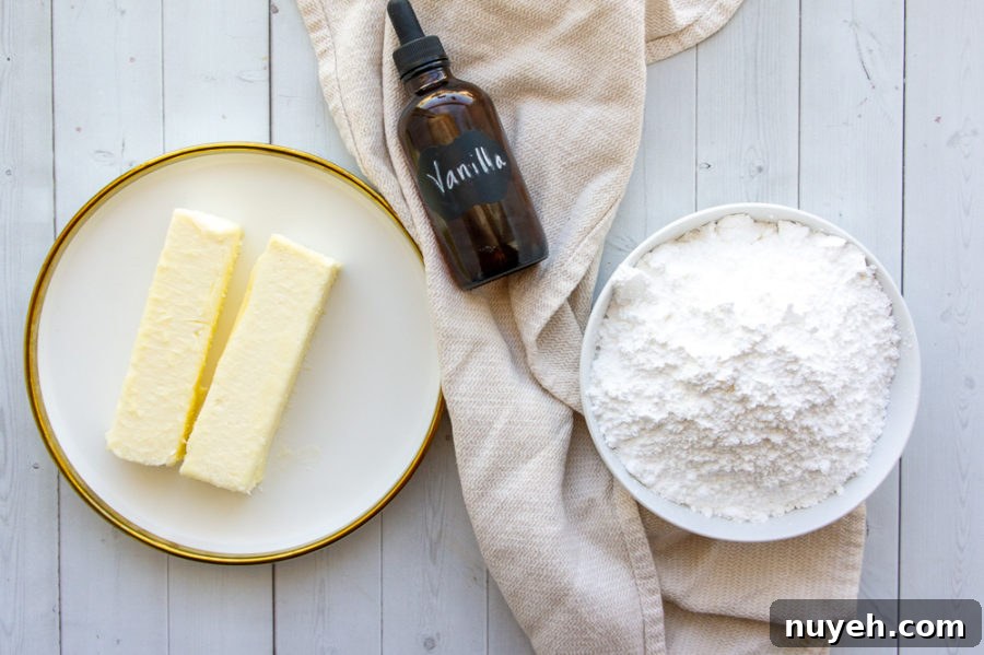 the 3 ingredients needed for vanilla buttercream, butter, powdered sugar, and vanilla on a white table
