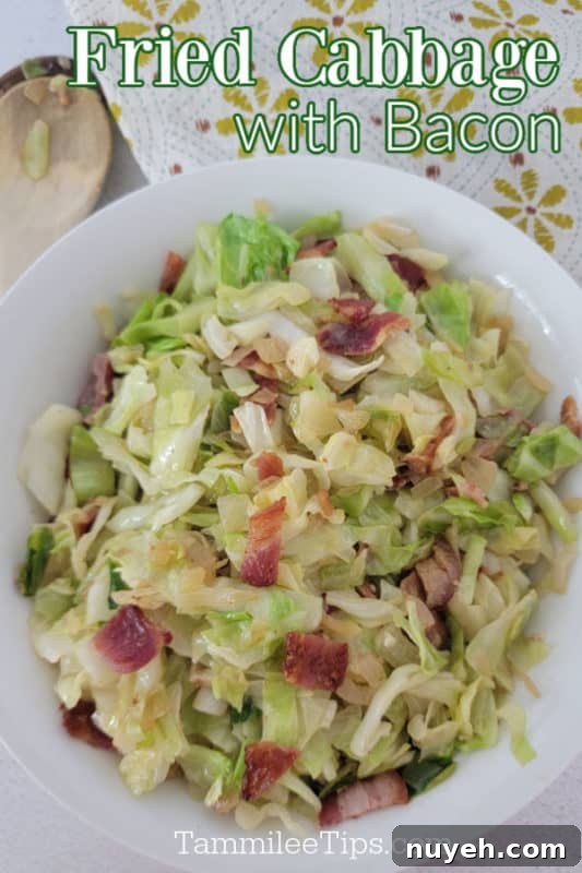 Fried Cabbage with bacon over a white bowl with cabbage and bacon next to a wooden spoon and cloth napkin