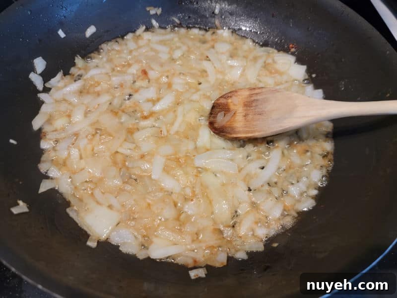 Wooden spoon in a frying pan with bacon and onions
