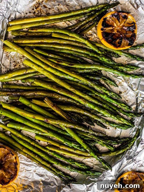 Grilled asparagus on tin foil with charred lemons.