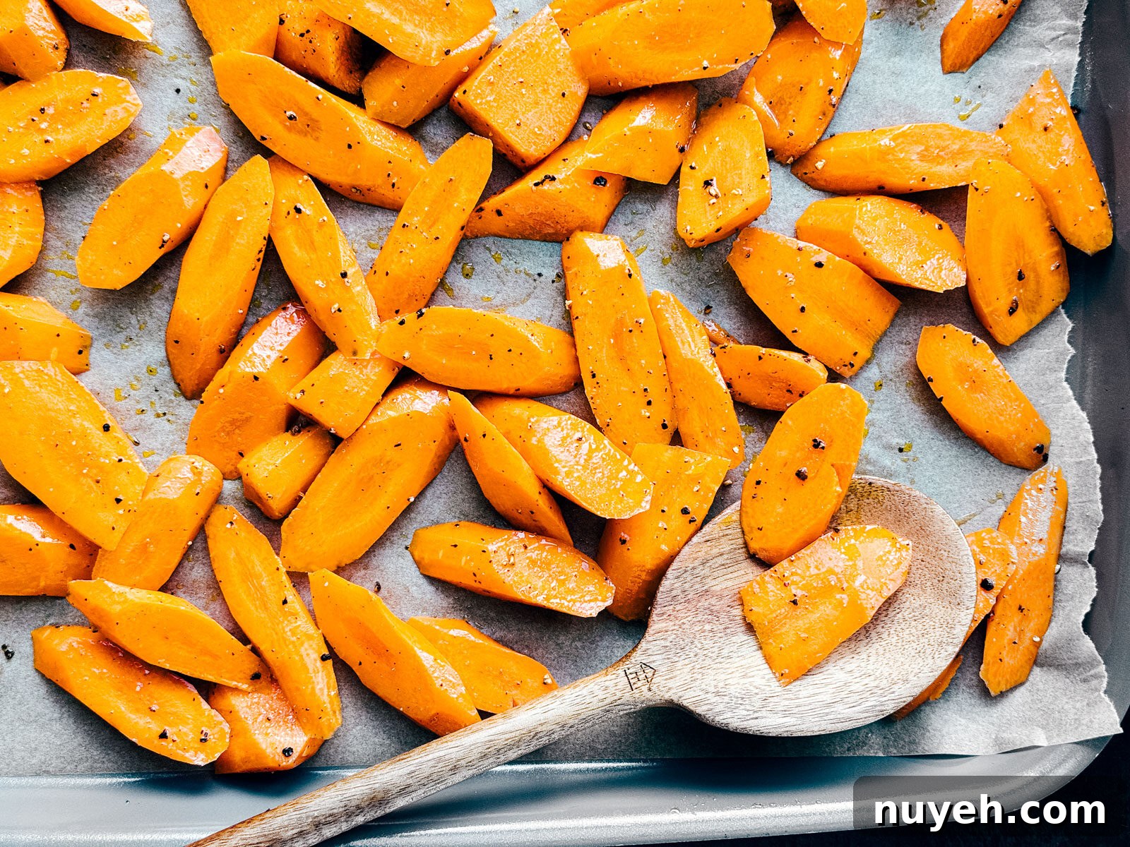 Sheet pan with carrots tossed in olive oil, salt, and pepper.
