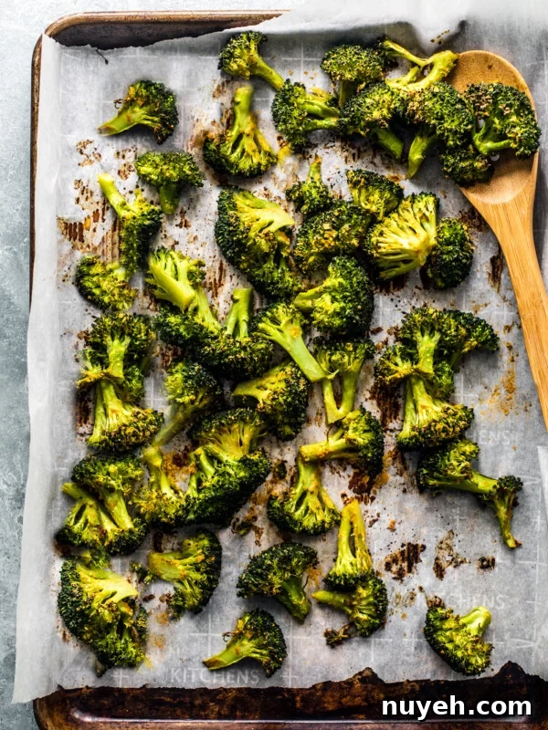 Sheet pan covered with parchment and roasted broccoli florets.