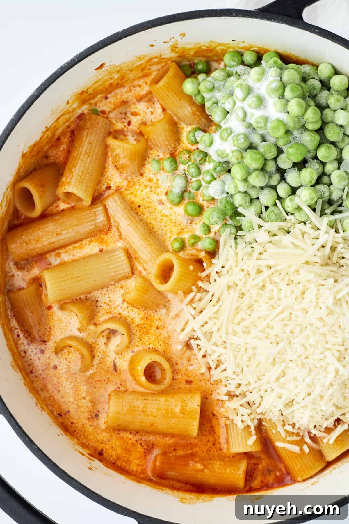 one pot spicy rigatoni in a pot topped with frozen peas and shredded Parmesan