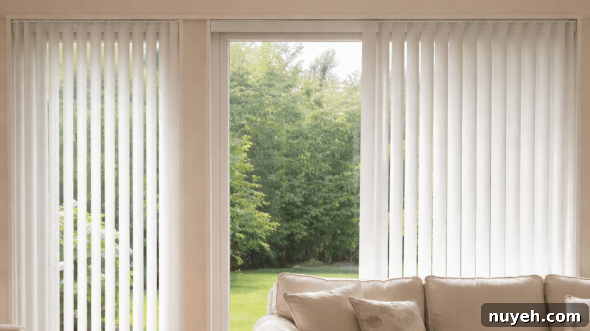 Shutters vs Blinds: Which Window Treatment Fits Your Home? 5 a cozy living room with white vertical blinds covering large windows, a beige sofa, with a garden view outside. png