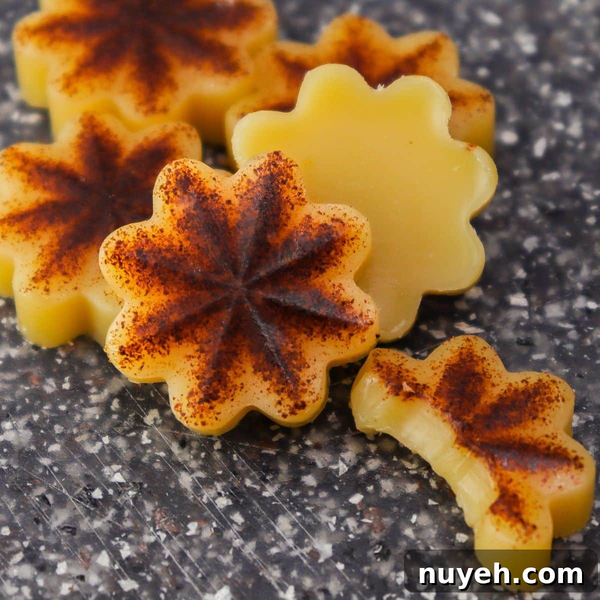 flower shaped brown butter bites on a black cutting board plus one with a bite taken out of it