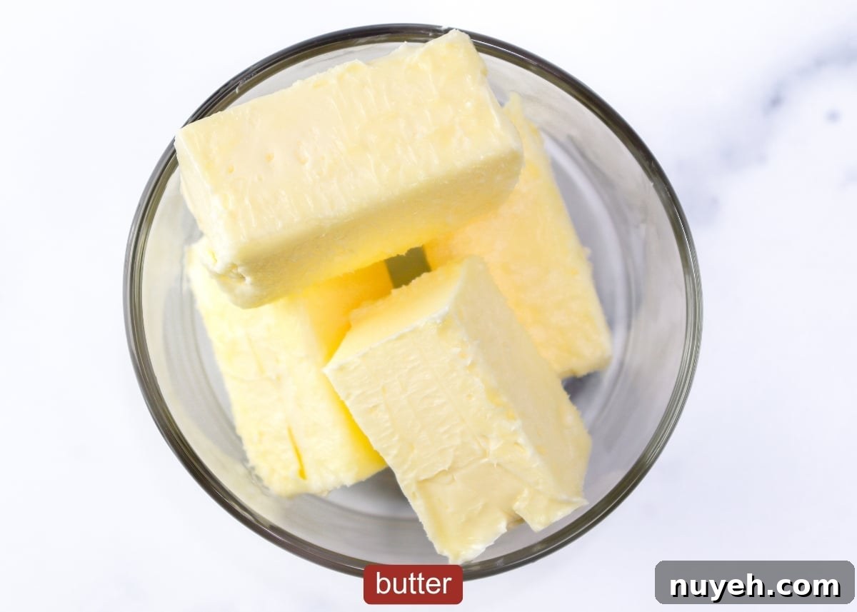 Two sticks of butter cut into 4 equal parts displayed in a glass container as one of the ingredients for this recipe