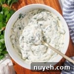 A bowl of chimichurri aioli with a gold spoon in it.