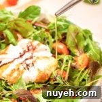 A bowl of burrata caprese salad with olive oil being poured over it.