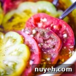 Closeup side view of marinated heirloom tomatoes in a pie dish.