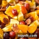 A closeup of Thanksgiving Fruit Salad with grapes, pears, apples, oranges, and pecans.