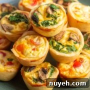A plate with a stack of mini quiches. Each quiche has a golden-brown crust filled with ingredients such as cheese, spinach, mushrooms, and chopped red peppers.