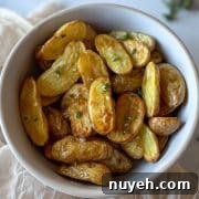 Air Fryer roasted fingerling potatoes dressed in olive oil, lemon juice, garlic, and thyme dressing with a white linen and thyme and lemon in the background.