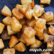 A plate of diced, crispy golden-brown roasted potatoes.