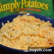 A blue bowl filled with cooked hash browns, topped with seasoning, is placed in front of a package of Simply Potatoes.