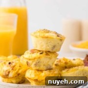 A plate with a stack of four mini quiches, surrounded by more mini quiches. In the background, there is a bottle and a glass of orange juice.