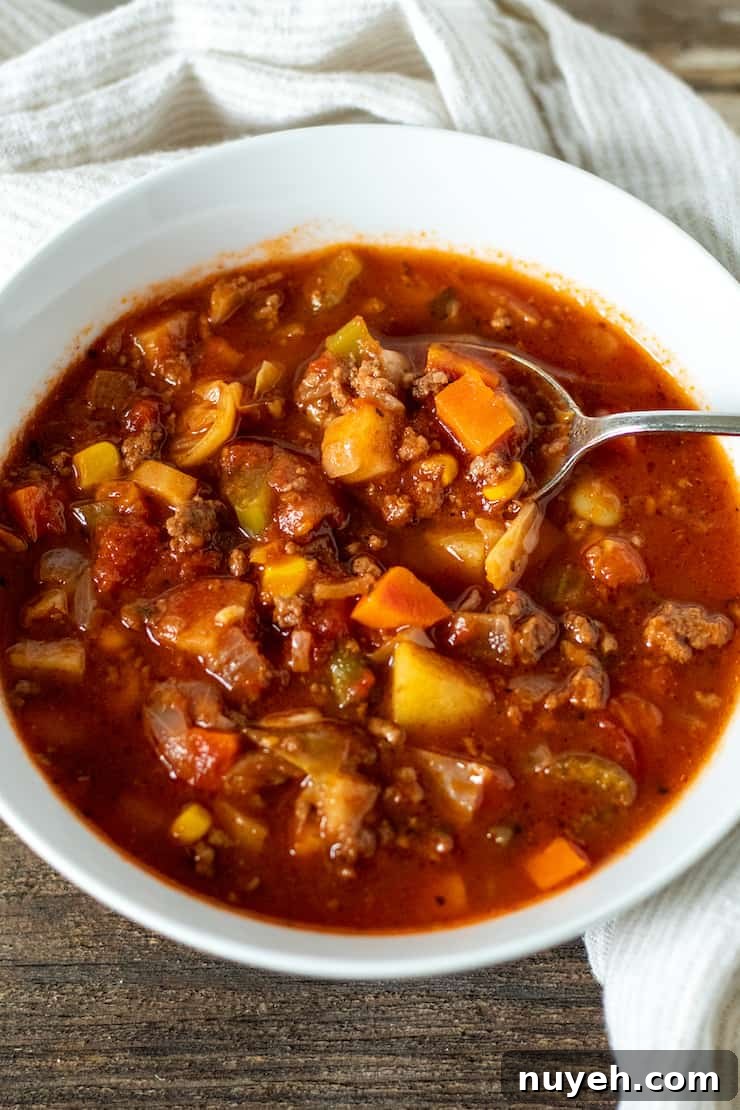 Vegetable beef soup in serving bowl with spoon.